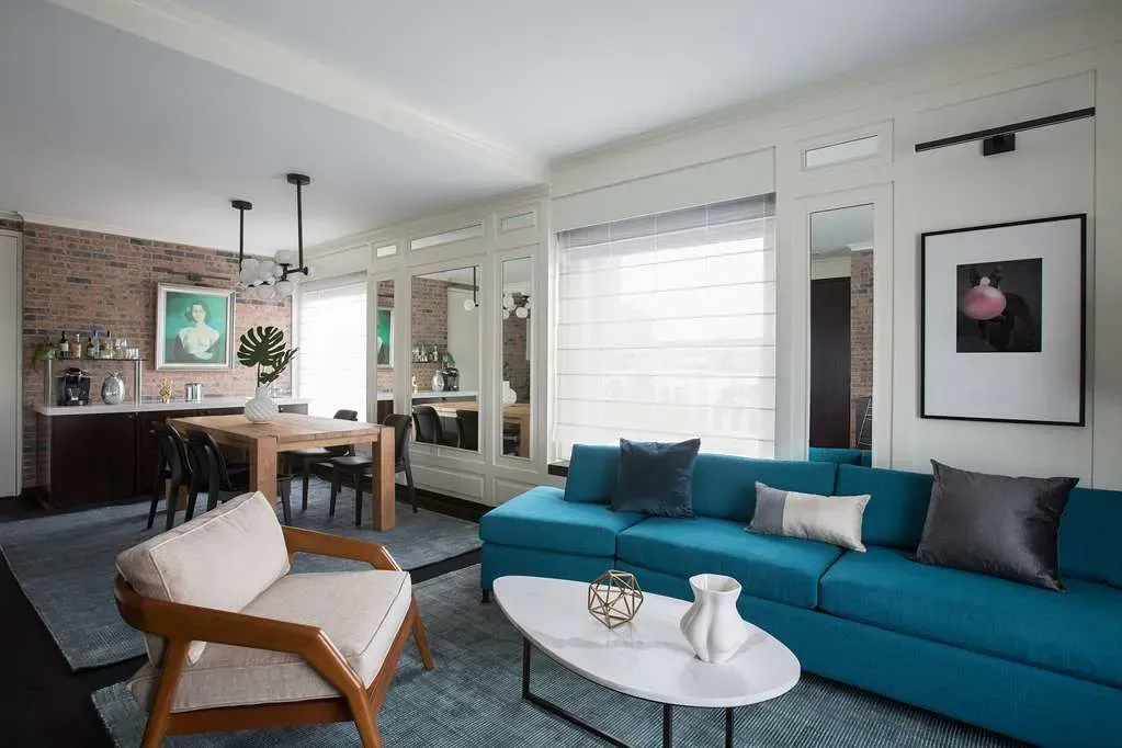 A suite living room, a teal sofa on a blue rug against exposed brick.