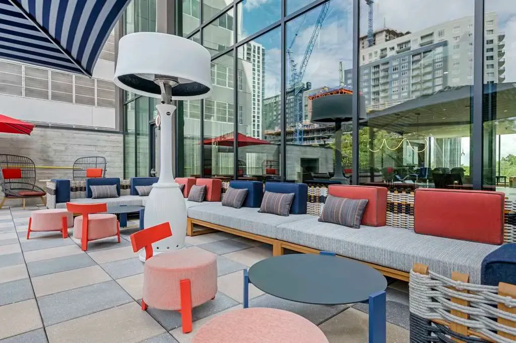 The patio terrace, navy and coral seating under a heat lamp beside the glass.