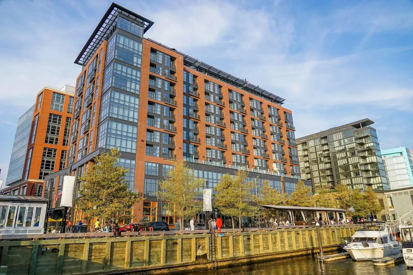 The hotel from the water, brick and glass stepping to a rooftop pavilion.