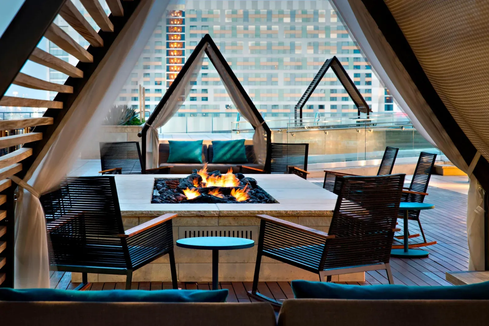 Cabanas drawn around a lit firepit on the deck, tower rising behind.