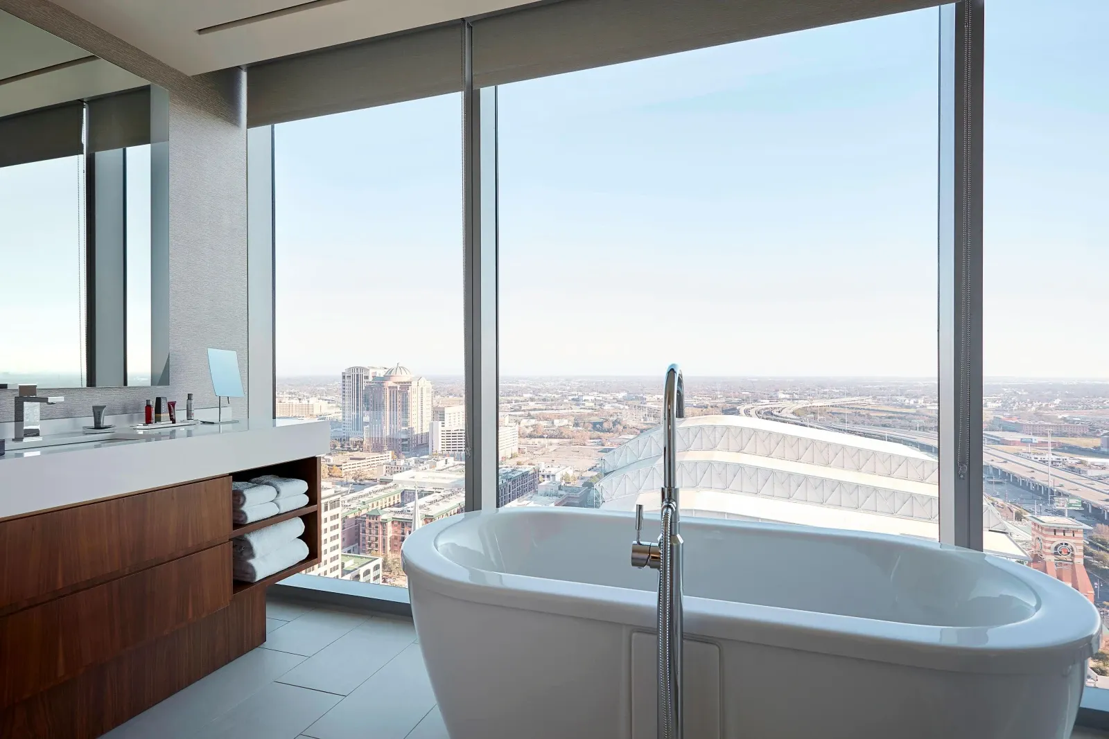 A freestanding tub at the glass, downtown Houston spread out below.