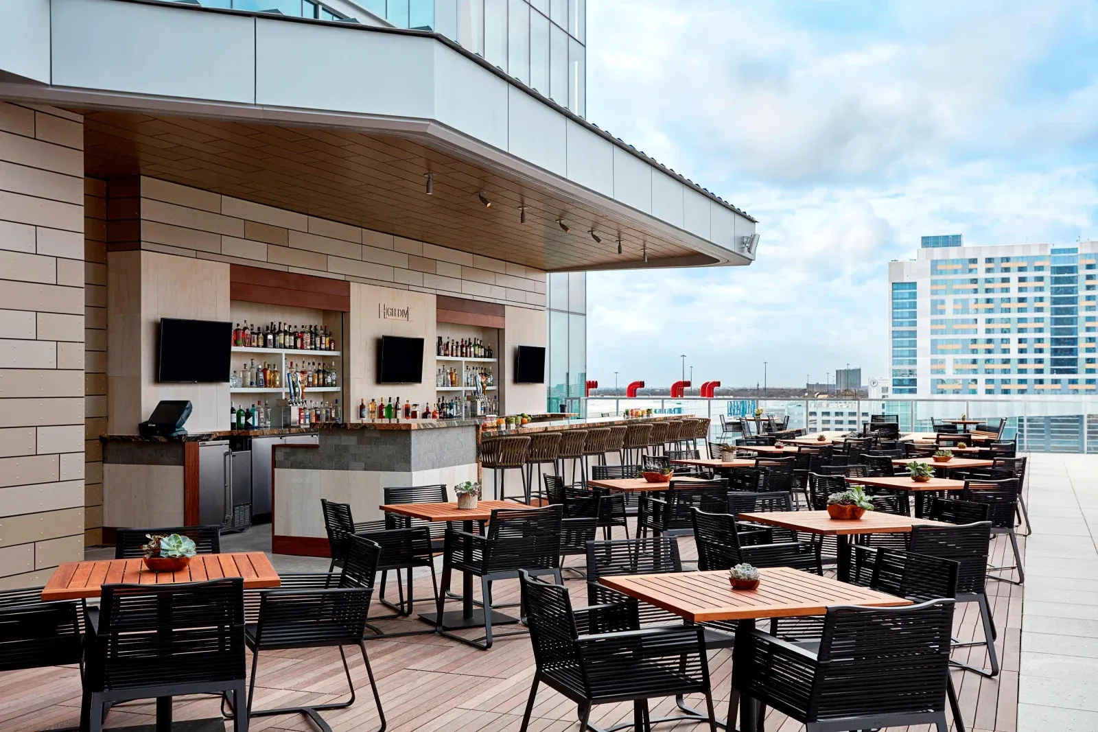 High Dive's outdoor bar and teak tables along the pool deck at midday.