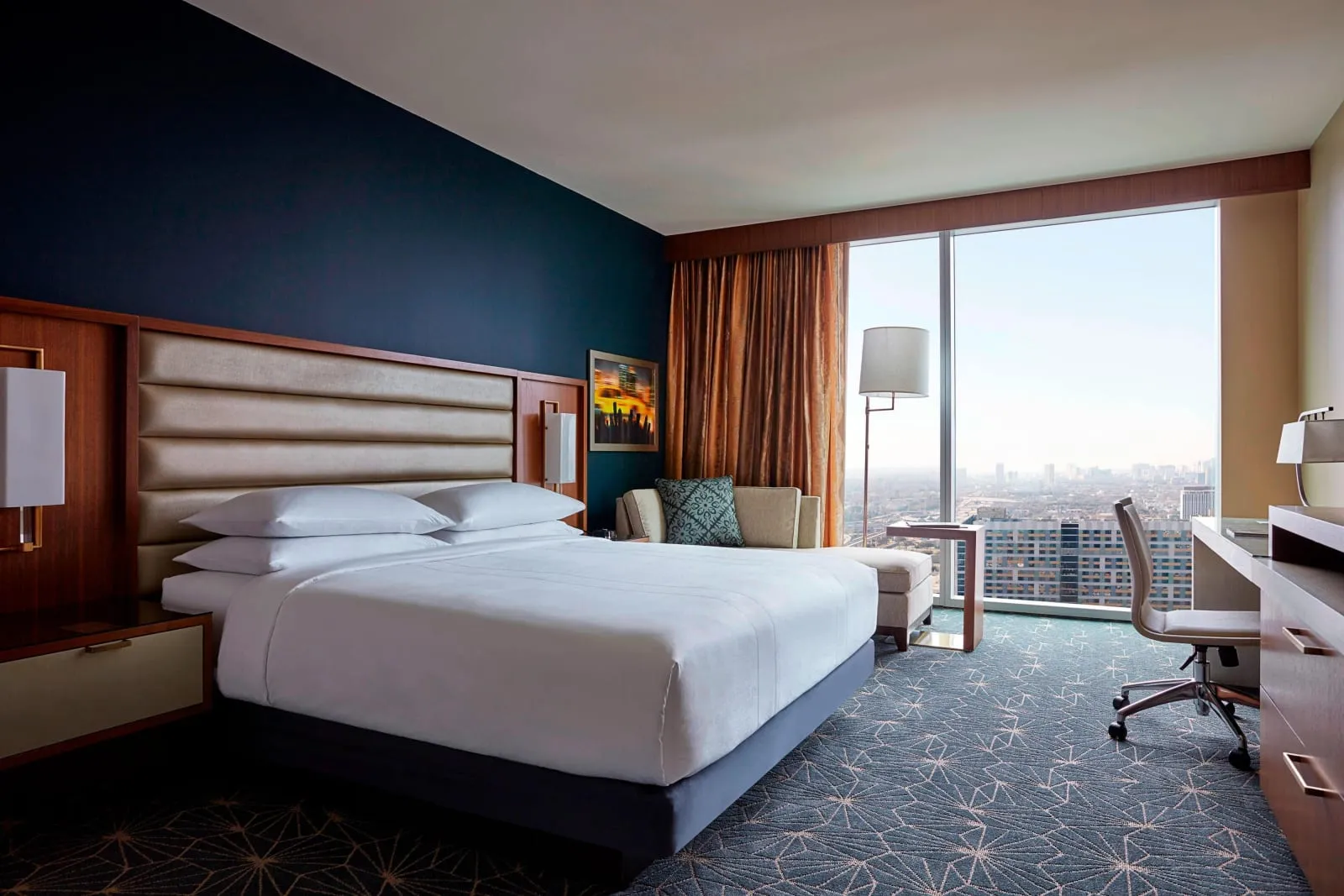 A king room in navy and walnut, floor-to-ceiling window onto the city.