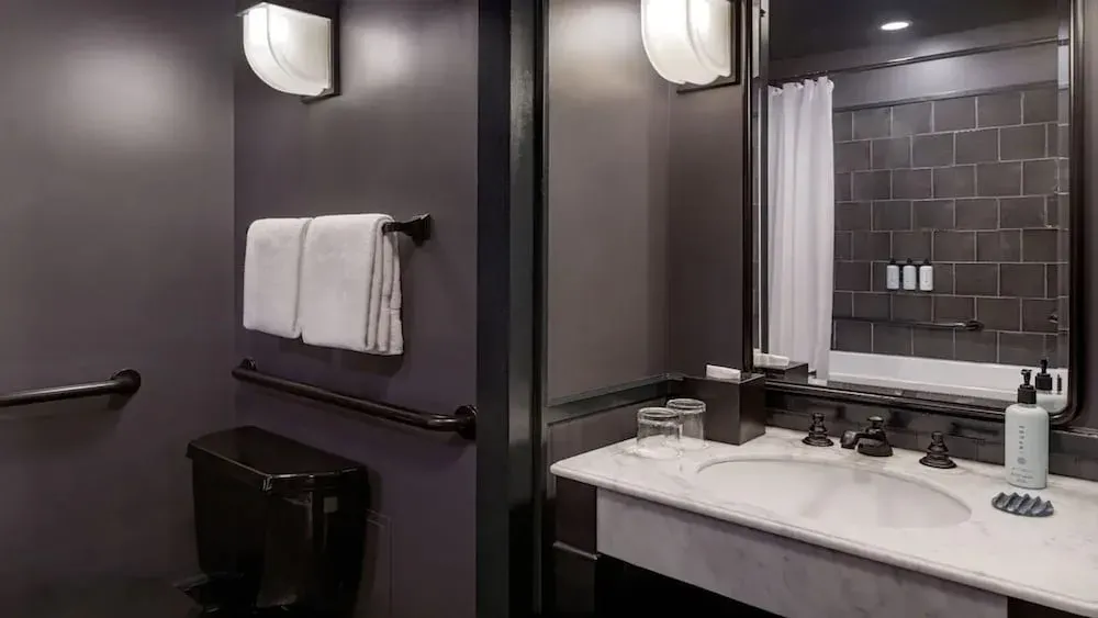 A bathroom in charcoal, marble washstand and a glazed tile shower behind.