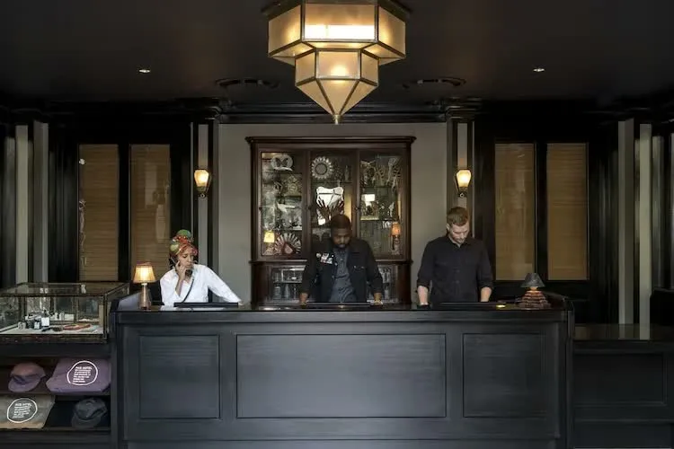 The check-in desk in black lacquer, an art-deco pendant lamp above.