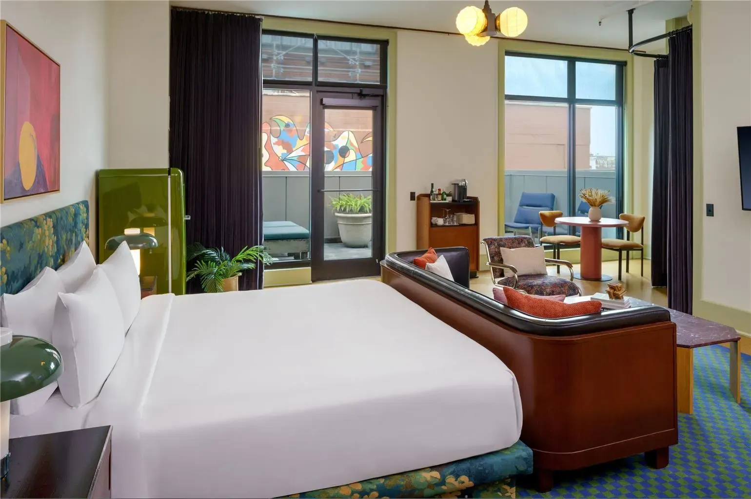 A guest room with a tall upholstered headboard and shuttered windows.