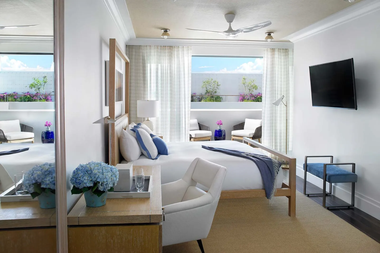 A white-and-blue room opening onto a private terrace with rattan armchairs.