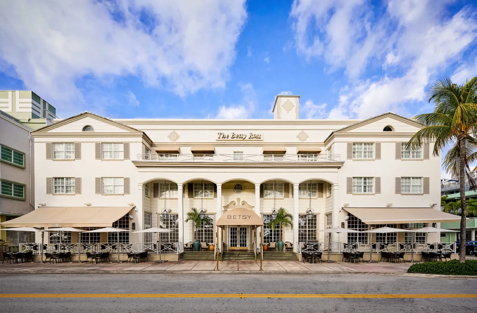 The Betsy's cream Colonial-revival facade on Ocean Drive, columned arcade and sidewalk tables.