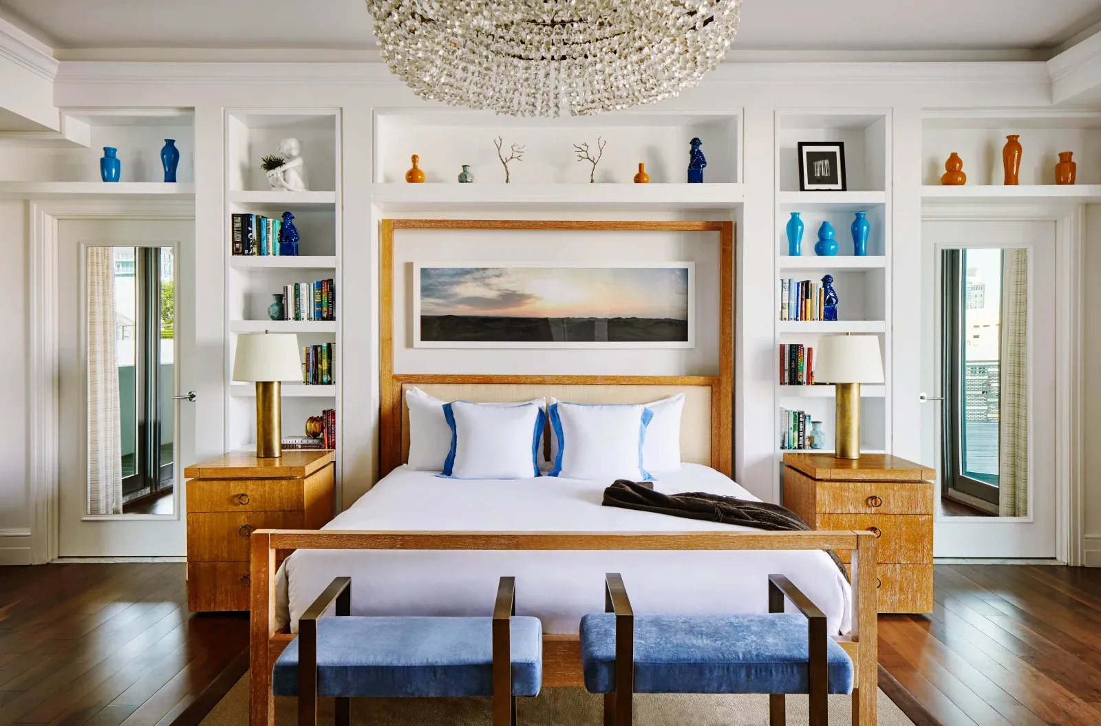 The Skyline Penthouse bedroom under a crystal chandelier, between built-in bookshelves.