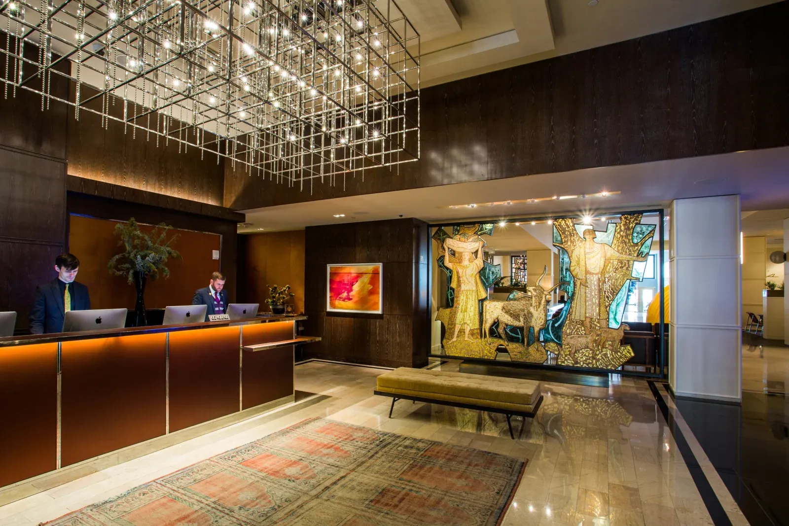 The reception desk in dark wood and bronze under a crystal chandelier.