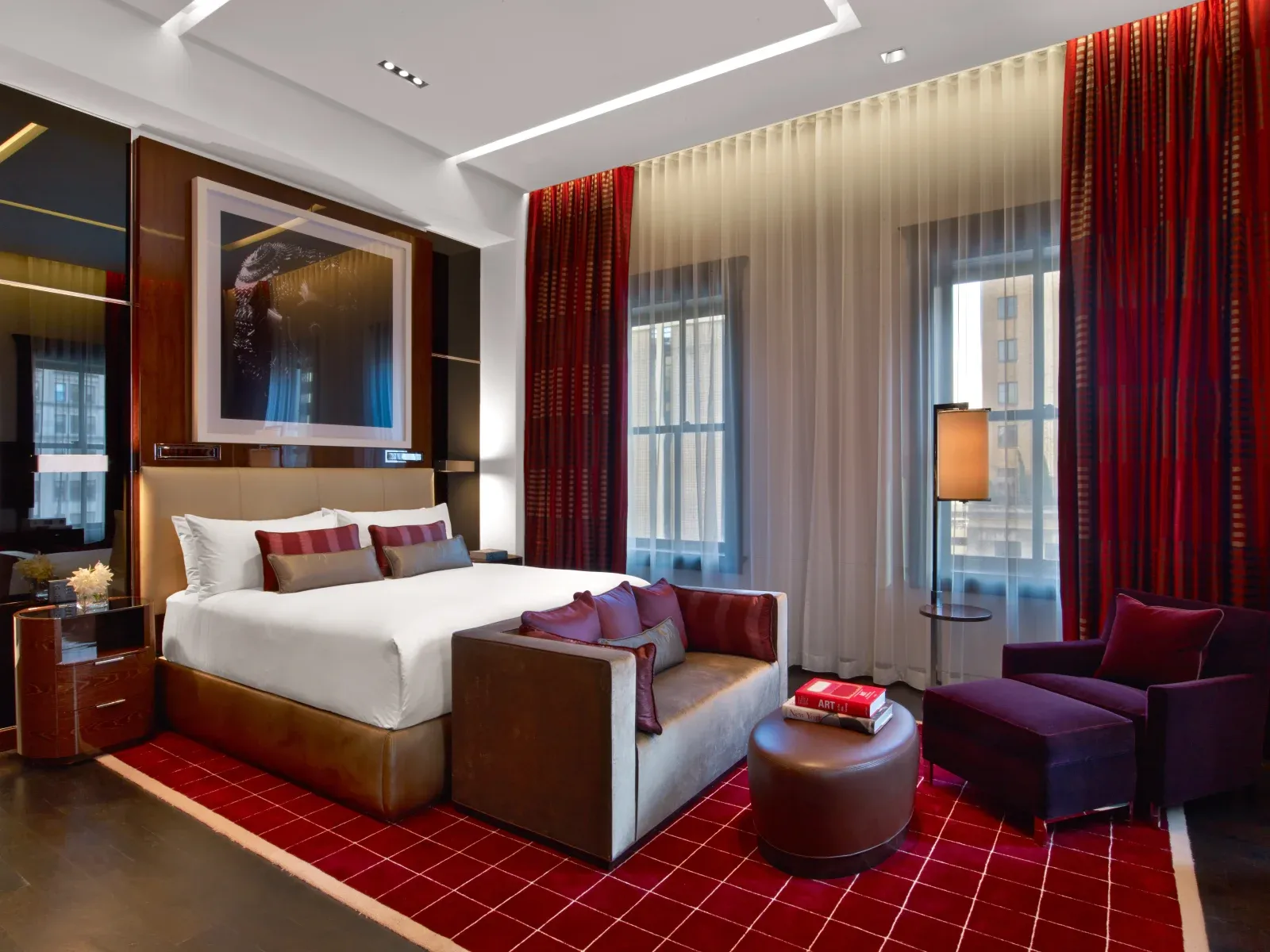 The Penthouse Loft, bed on a red grid carpet between full-height windows.