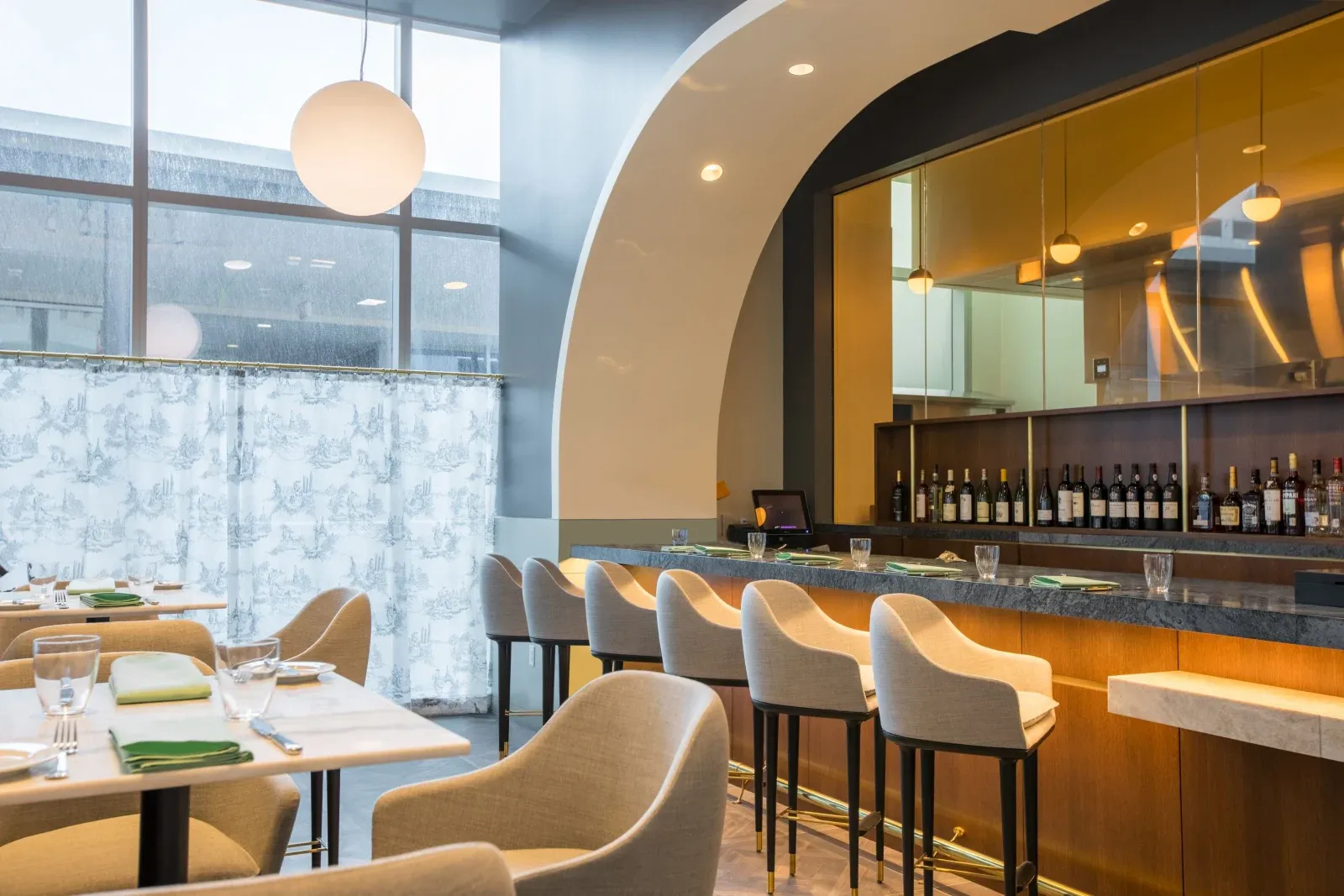 Hull Oak's marble bar under an arch, pale stools and a globe pendant.