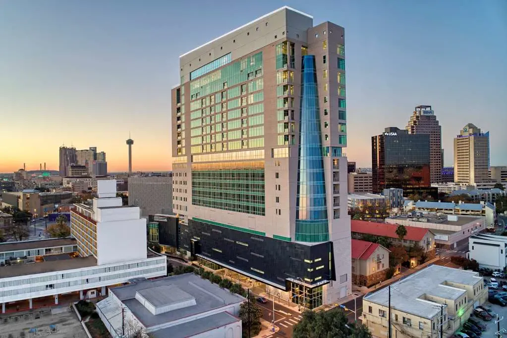The tower at dusk, green glass and a curved blue spine above downtown.