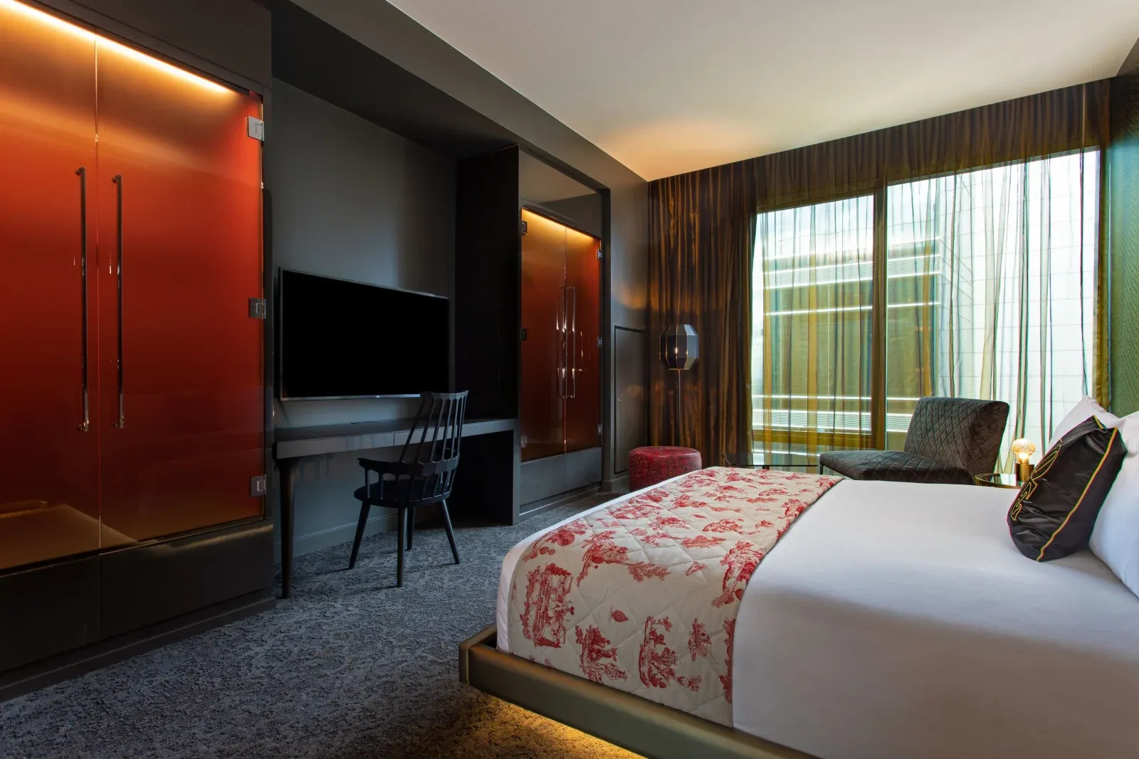 A suite bedroom, red-lit glass doors beside the bed and a toile runner.