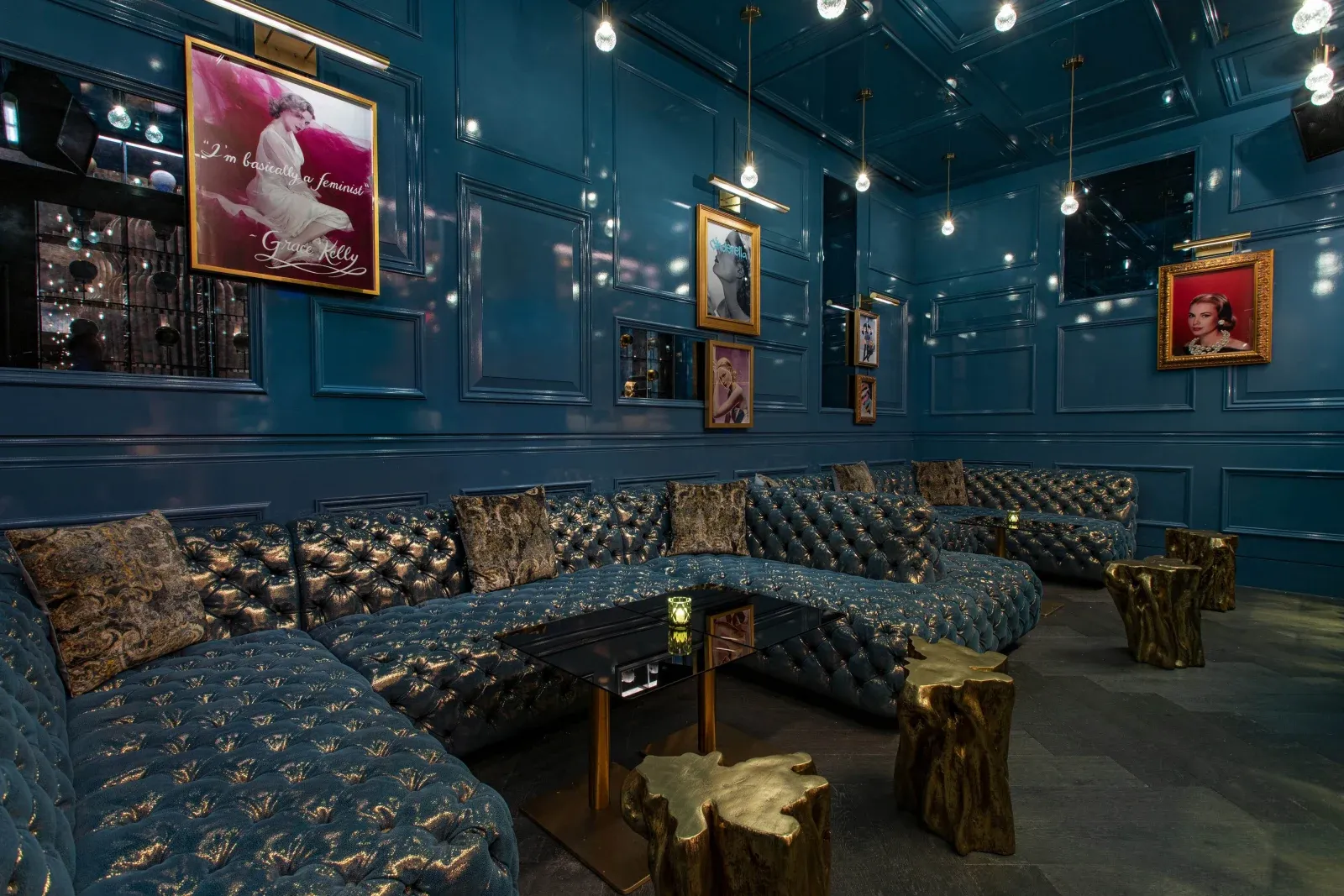 A teal lounge, tufted banquettes and gilt-framed portraits under pendant lights.